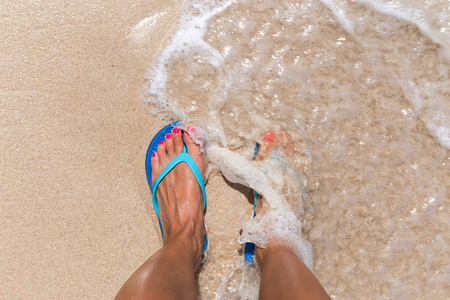 女人的腿站在海水热带的海滩上