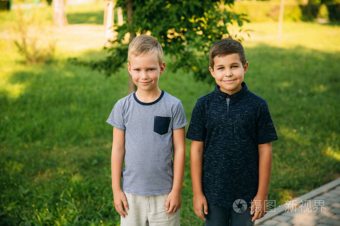 两个穿着 t恤衫和短裤的漂亮男孩笑得很开心.他们吃冰淇淋, 跳, 跑.