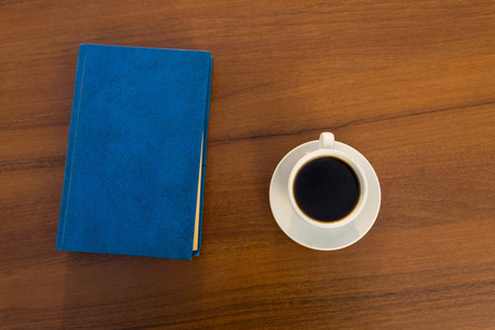 一杯咖啡和一本封闭的书在木桌上