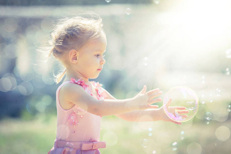 一个小女孩在夏日公园里捕捉肥皂泡沫