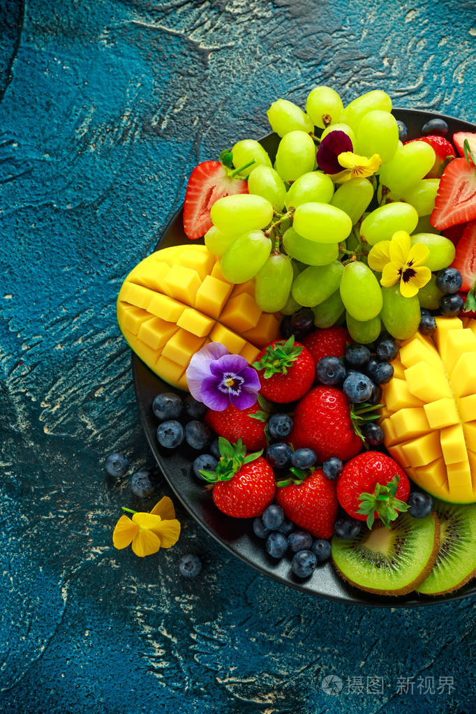 多彩的混合水果拼盘与芒果草莓蓝莓猕猴桃和绿葡萄健康的食物