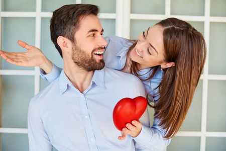 一对相爱的情侣带着一颗红色的心微笑照片