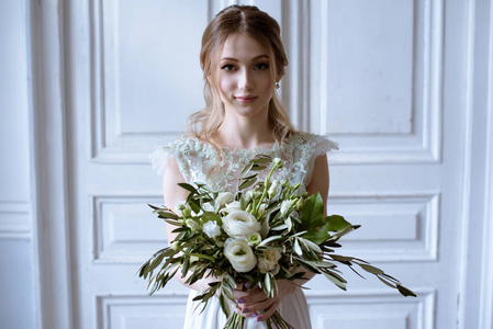 美丽的新娘在婚纱与室内的花束图片