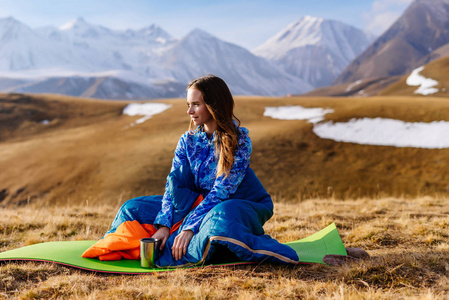 年轻的女孩游客坐在高山和饮茶的背景
