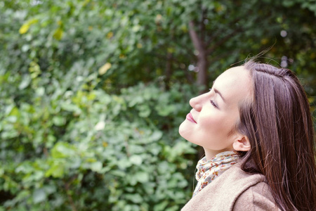 微笑的妇女与一个完美的微笑, 走在秋季公园的大衣和看着相机