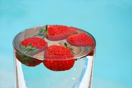 水中的草莓一个草莓浆果掉进水中的蓝色背景美草莓在蓝色背景上的泡沫