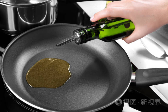 女人把油从瓶子里倒进煎锅