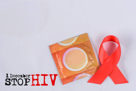 白色背景的红色艾滋病宣传带和避孕套