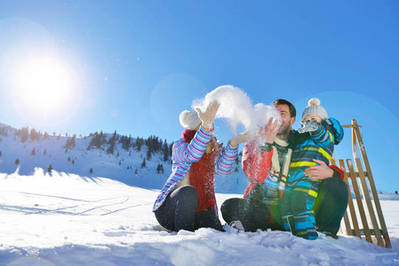 幸福年轻的家庭，在新鲜的雪打美丽晴朗的冬日户外性质