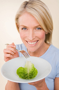 漂亮健康的白种女人拿着生菜板与米色背景