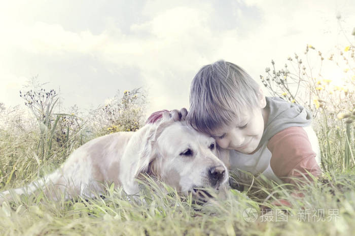 可爱的小男孩亲切地拥抱他的狗在自然中间