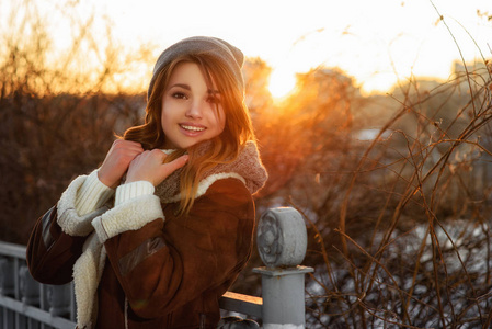 夕阳下欢快的年轻女子的特写冬季肖像。辉光太阳