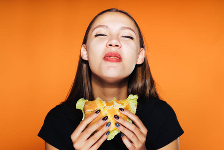 饿了的女孩想要减肥，但急切地吃有害的汉堡