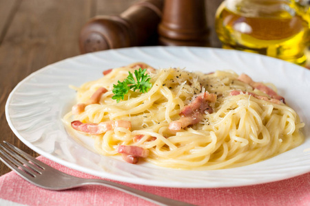 经典的面食 carbonara。意大利面配培根，鸡蛋蛋黄和帕尔玛奶酪在白板上深色木制背景