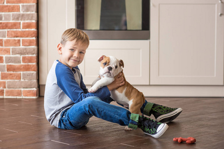 逗人喜爱的男孩玩小狗英国斗牛犬照片