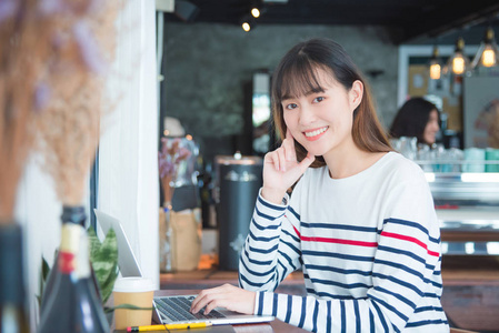 年轻的亚洲美丽的女孩使用笔记本电脑