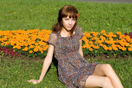 美丽的女孩坐在草地上，开着花