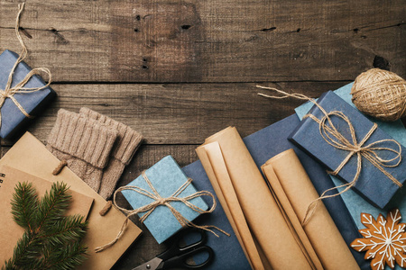 用老式的米色蓝色卷纸在旧木桌上包装圣诞礼物。顶部视图。平躺。复制空间