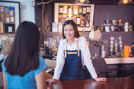 美丽的咖啡师与她的顾客交谈和微笑在咖啡馆