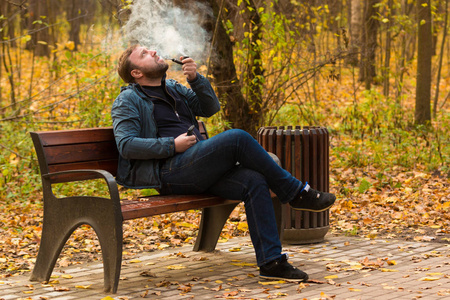 烟草管年轻人吸烟烟草管在公园照片