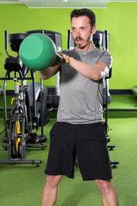 健壮的男人专注于他在健身房的壶锻炼
