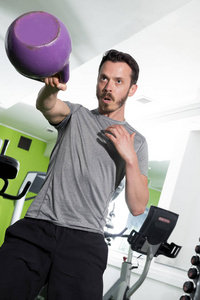 健壮的男人用紫色的壶在健身房锻炼