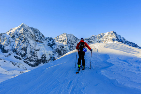 走上沿与白雪皑皑的山脊的登山野外滑雪