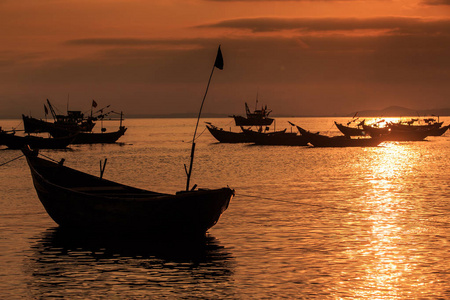 海面上的越南渔船剪影在明亮的日落反射