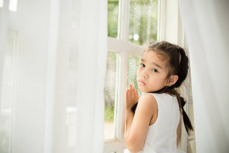 沮丧的小女孩在家附近的窗口