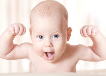 强壮的婴儿笑着举起双手。 微笑的孩子