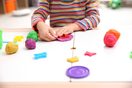 小女孩从事 playdough 建模在桌