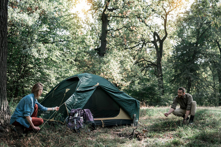 快乐的男人和女人搭帐篷在森林里