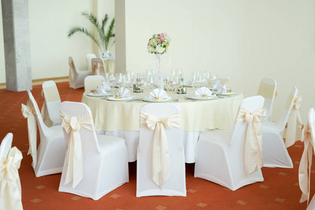 美丽婚礼花艺装饰的餐厅，在桌上。洁白的桌布，明亮的房间里