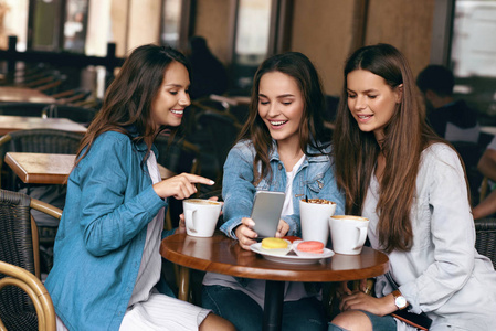 年轻的女性朋友在咖啡馆里使用电话和喝咖啡