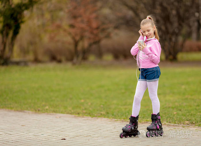 美丽微笑的小女孩在公园内滑冰和听音乐
