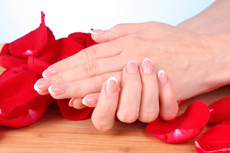 玫瑰花瓣上有美甲的女人的双手图片