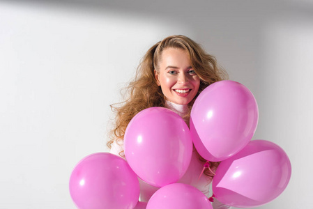 美丽的微笑的女孩与捆绑粉红色气球