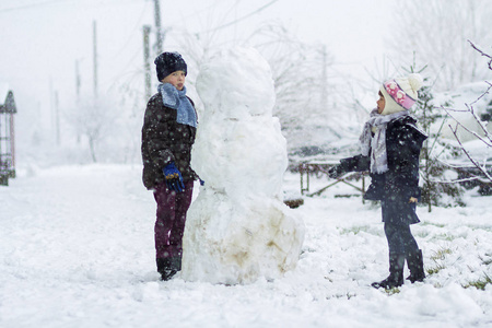 儿童男孩和女孩在下雪的冬天在户外做一个大