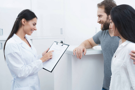 一个男人和一个女人来看牙医。接待员填写表格并采访病人