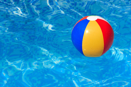 一个五颜六色的沙滩球浮在游泳池里
