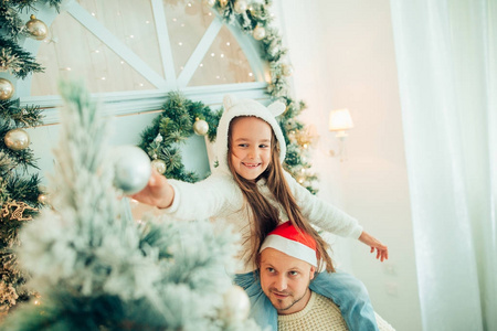 女孩帮助父亲装饰圣诞树, 拿着一些圣诞小