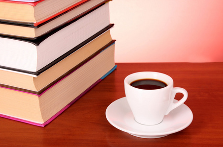书堆和一杯咖啡放在桌子上，红色背景