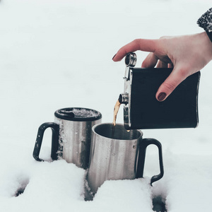 冬季雪中倒入咖啡杯的妇女的部分看法