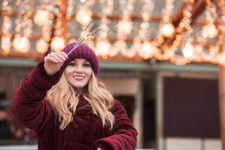 迷人的金发女孩手持发光的孟加拉灯在 Christm