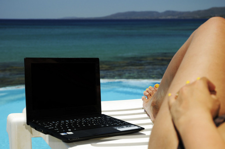 有笔记本电脑的女人在海边休息