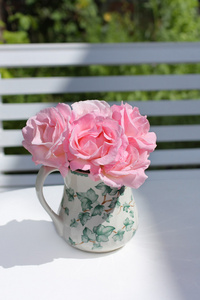 白色桌子上花瓶里的粉红色花园玫瑰