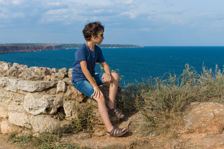 望向天空男孩坐在高高的海滨, 望向远方照片