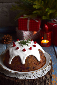 传统英语圣诞蒸布丁与冬季浆果, 干果, 坚果在节日的设置与圣诞树和燃烧的蜡烛。水果蛋糕