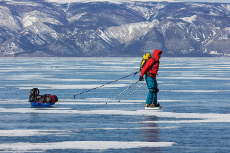 男性徒步旅行者与背包站立在冰水表面, 俄国, 贝加尔湖
