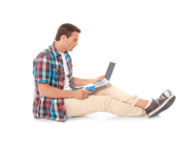 年轻男子手持笔记本电脑和信用卡在白色背景